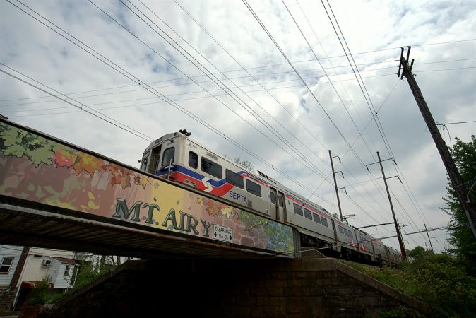 A SEPTA train on the Chestnut Hill West line crosses Mt Pleasant Avenue as it is on its way to Center City. The trestle is part of the Mural Arts Program and made possible with support of Mt Airy residents, (including Ken Weinstein). (Bastiaan Slabbers for WHYY)