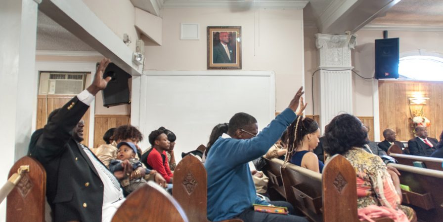 Pews are filled with members during Sunday morning service.  A photo of Bishop Eugene H. Graves hangs in the sanctuary in his memory.