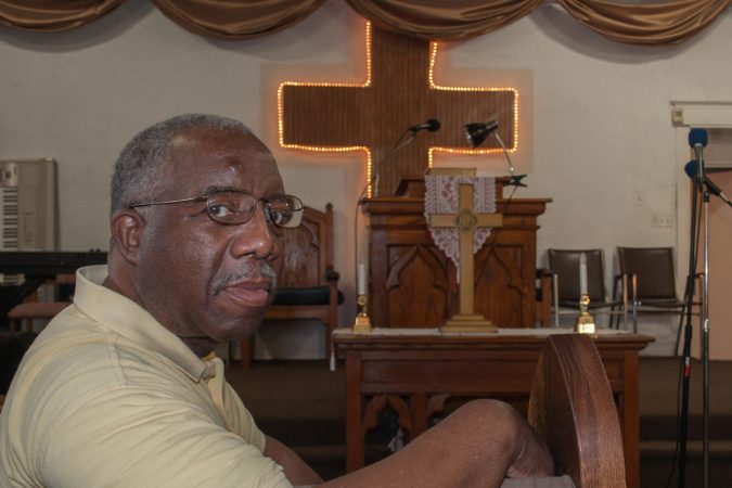 Deacon Harding sits for a portrait before returning to his work of cleaning and preparing the space for Sunday service