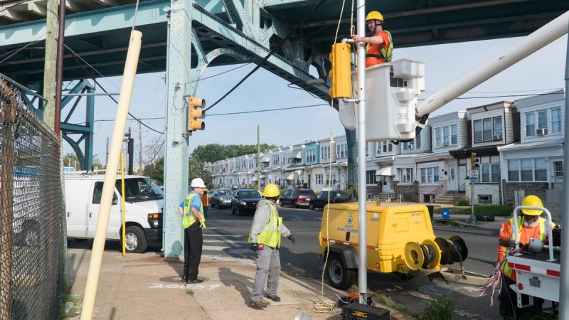 The Streets and Traffic team works above and on the ground to repair a signal. (Branden Eastwood for WHYY)