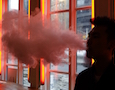 a man exhales vapor from an e-cigarette