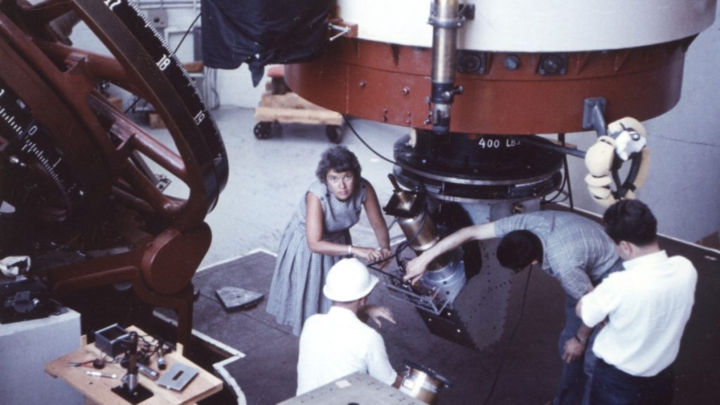 Vera Rubin at Lowell Observatory in 1965. Kent Ford, her longtime collaborator is kneeling in the hard hat. (Photo by Bob Rubin)
