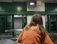 A female inmate sits in a single cell
