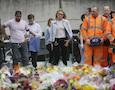 City workers and others stand after laying flower tributes in the London Bridge area of London