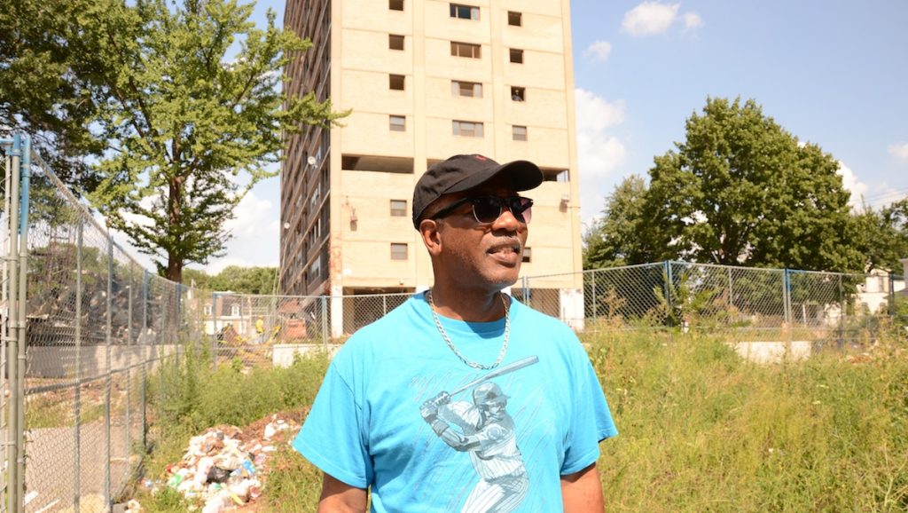 2-3 The windows to the second-floor apartment Neil Blunt grew up in can be seen behind him. (Jimmy Viola/for NewsWorks)