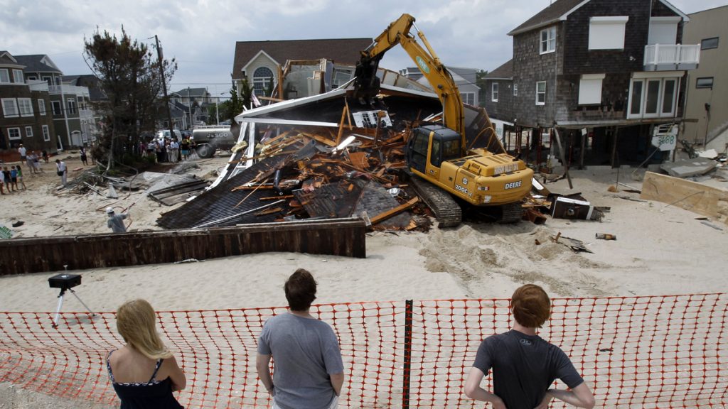 Superstorm NJ Demolitions People watch from the beach Wednesday, July 10, 2013, as a home severely damaged by Superstorm Sandy is demolished in the Normandy Beach section of Toms River, N.J. (Mel Evans/AP Photo, file)