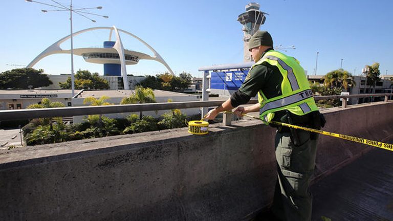  A police officer closes a road at the Los Angeles International Airport on Friday Nov. 1, 2013, after shots were reporter in Terminal 3, prompting authorities to evacuate the terminal and stop flights headed for the city from taking off from other airports. (AP Photo/Ringo H.W. Chiu) 