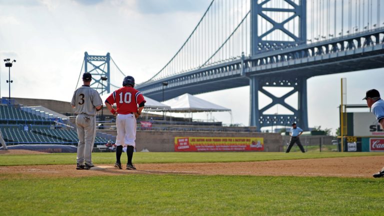  Dayton baseball player Mel Skochdopole (No. 10) stands on first base in an Atlantic 10 tournament game, with the Ben Franklin Bridge in the background on May 25, 2011 in Camden, N.J. (Photo via Shutterstock) 