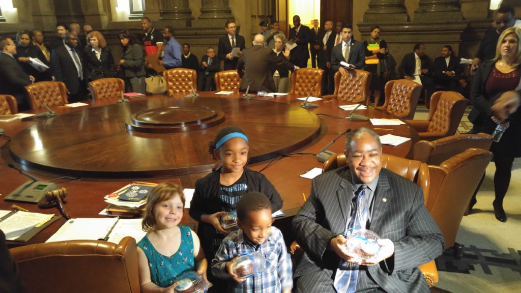 20151029_095745 Philadelphia students brought cupcakes to the Thursday meeting of City Council in thanks for a $25 million infusion to the struggling school district. Seated with some of the children, Councilman Wilson Goode Jr.is all smiles. (Tom MacDonald/WHYY)