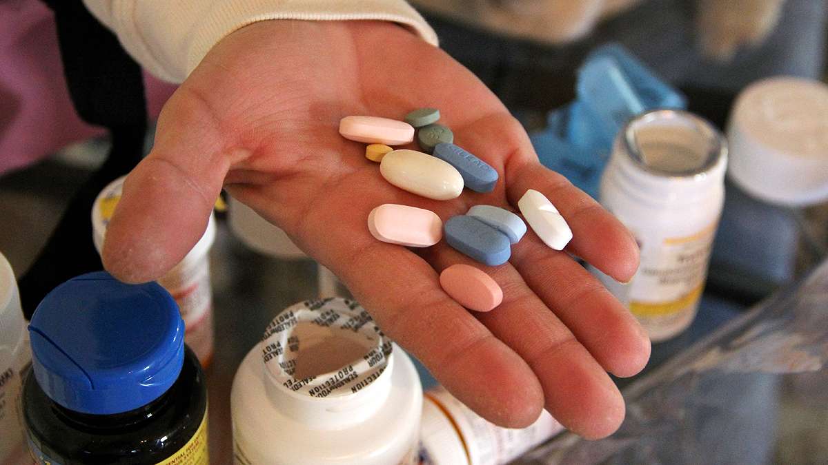 Philadelphia AIDS survivor Suellen Kehler holds some of the more than 20 medications and supplements she takes each day to keep her HIV infection under control.