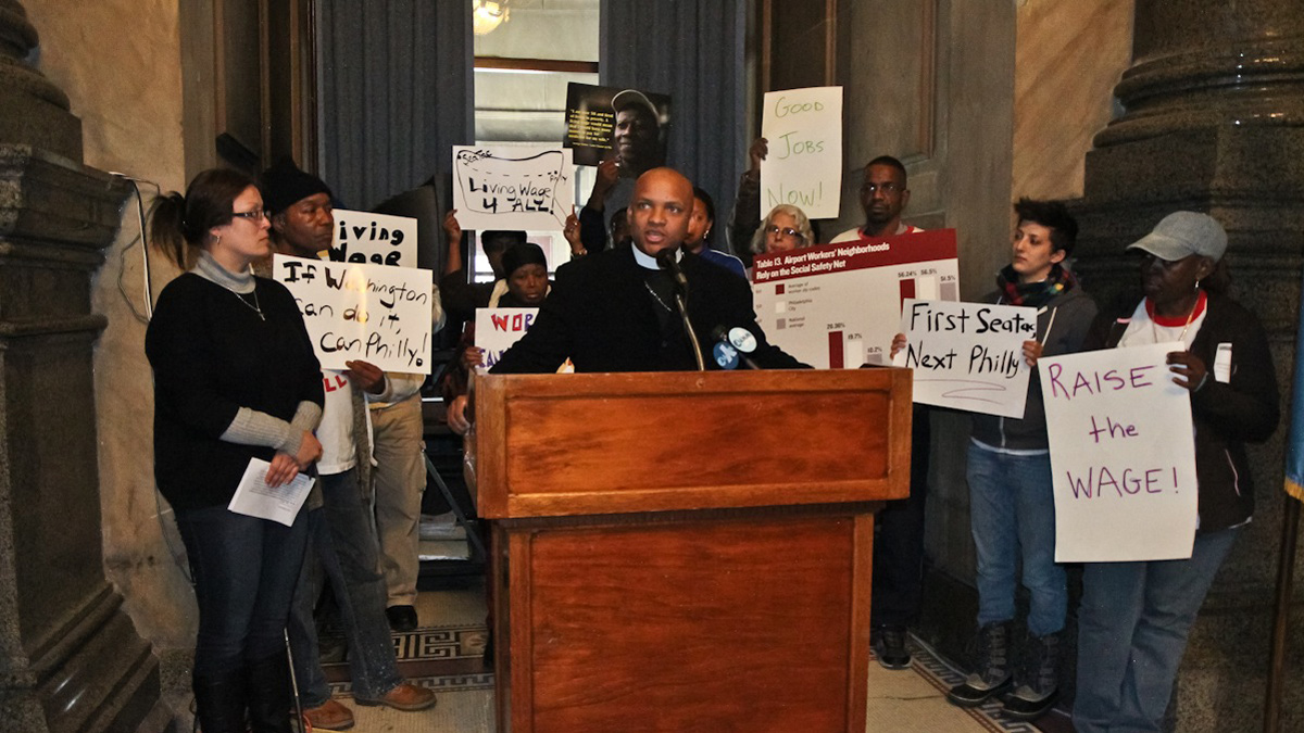  Rev. Cean James encourages voters to support paying airport workers higher wages Friday at City Hall. (Kimberly Paynter/WHYY) 
