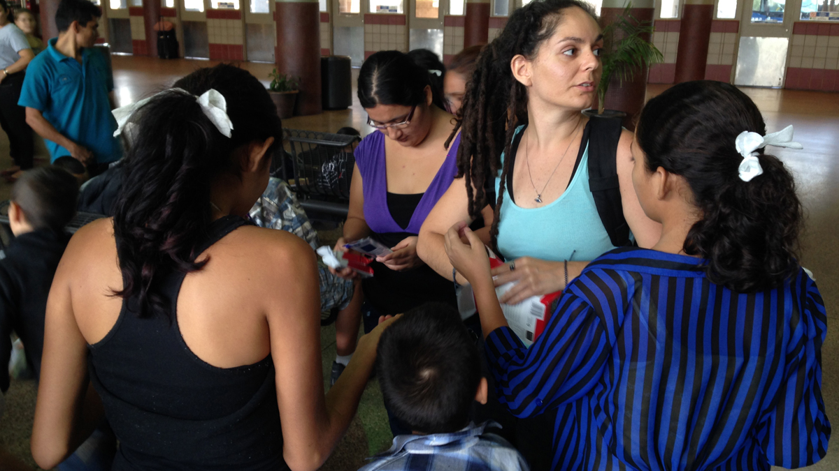  Volunteer Layal Rabat from the Phoenix Restoration Project brings water, food and diapers to Central American women and their children dropped off at the Greyhound bus station in Phoenix in May. (Valeria Fernández/AP Photo) 