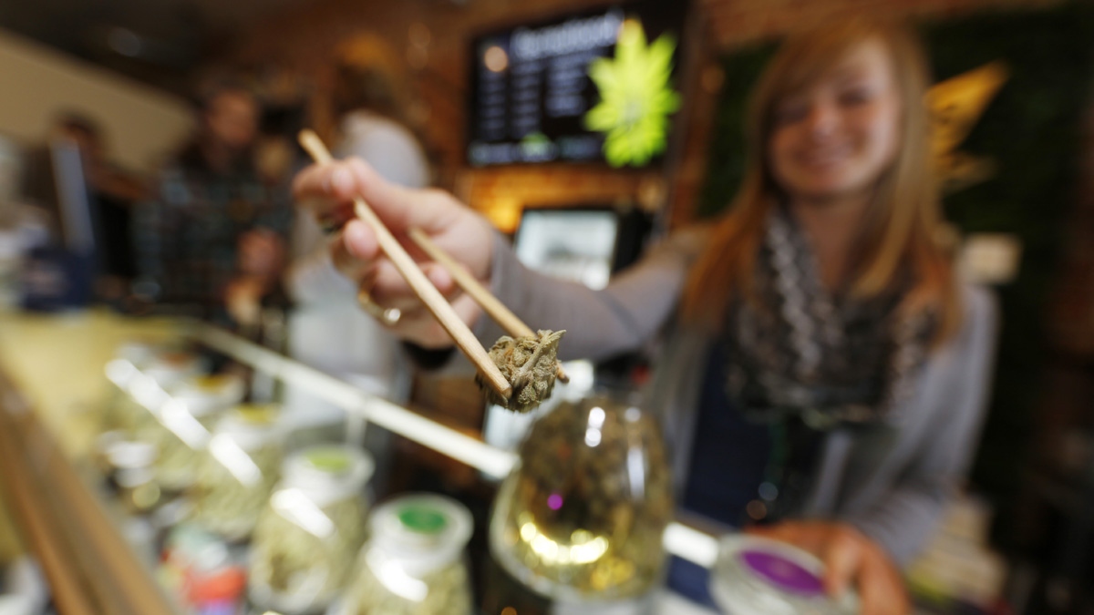 LivWell store manager Carlyssa Scanlon shows off some of the products available in the marijuana line marketed by rapper Snopp Dogg in one of the marijuana chain's outlets south of downtown Denver. Advocates of legalizing recreational pot in New Jersey say the Garden State could reap about $300 million a year through taxes on such products. (AP Photo/David Zalubowski