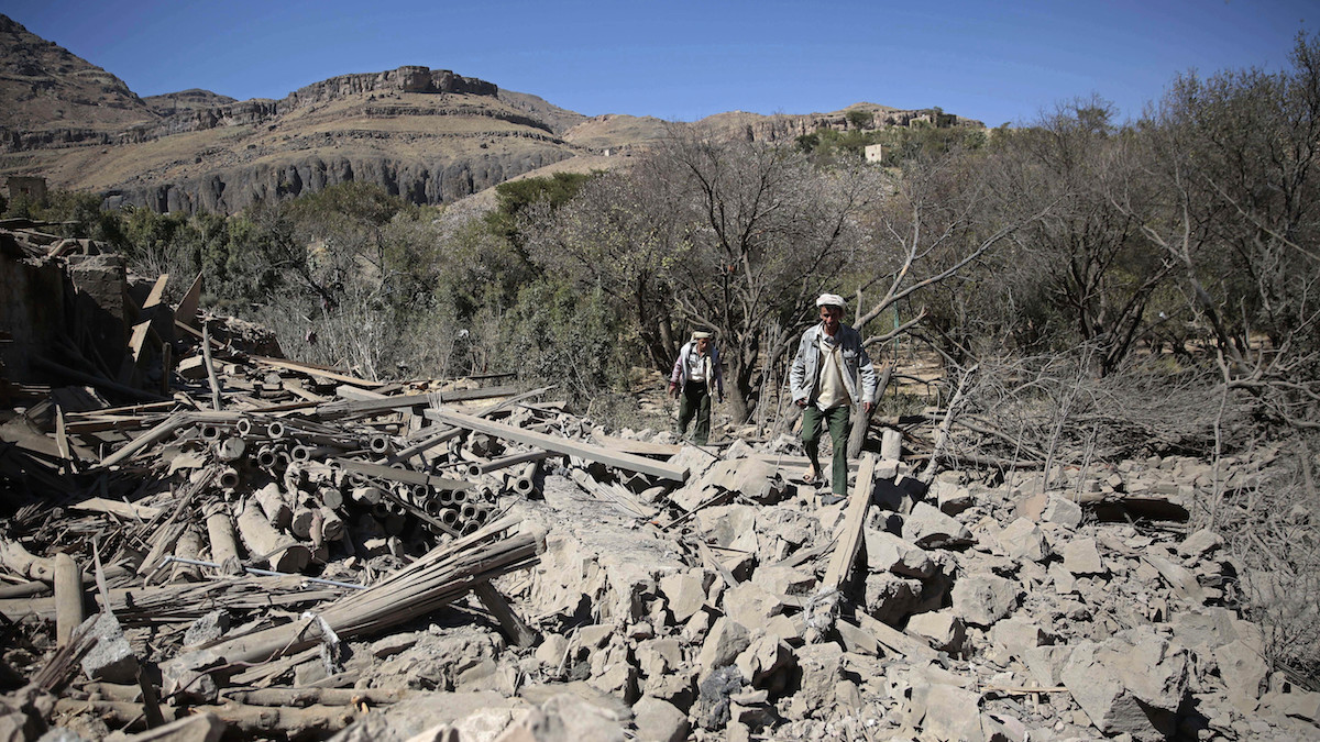 Men walk amid the rubble of a house destroyed by a Saudi-led airstrike on the outskirts of Sanaa