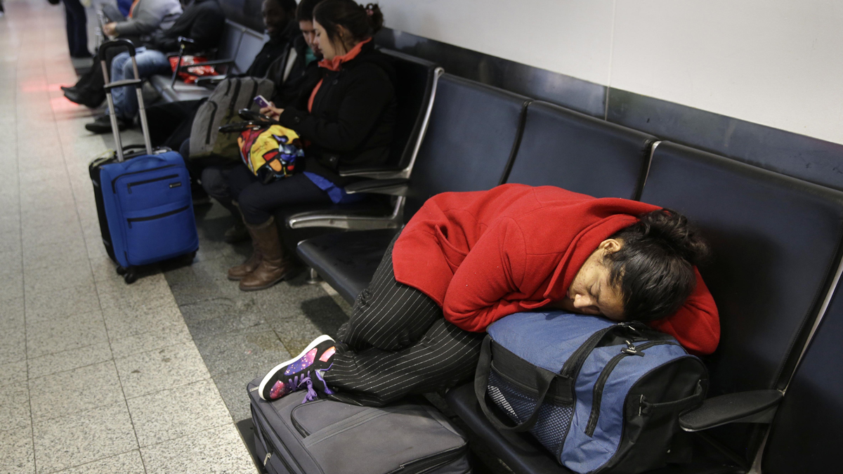 A woman sleeps on top of her luggage at LaGuardia Airport in New York