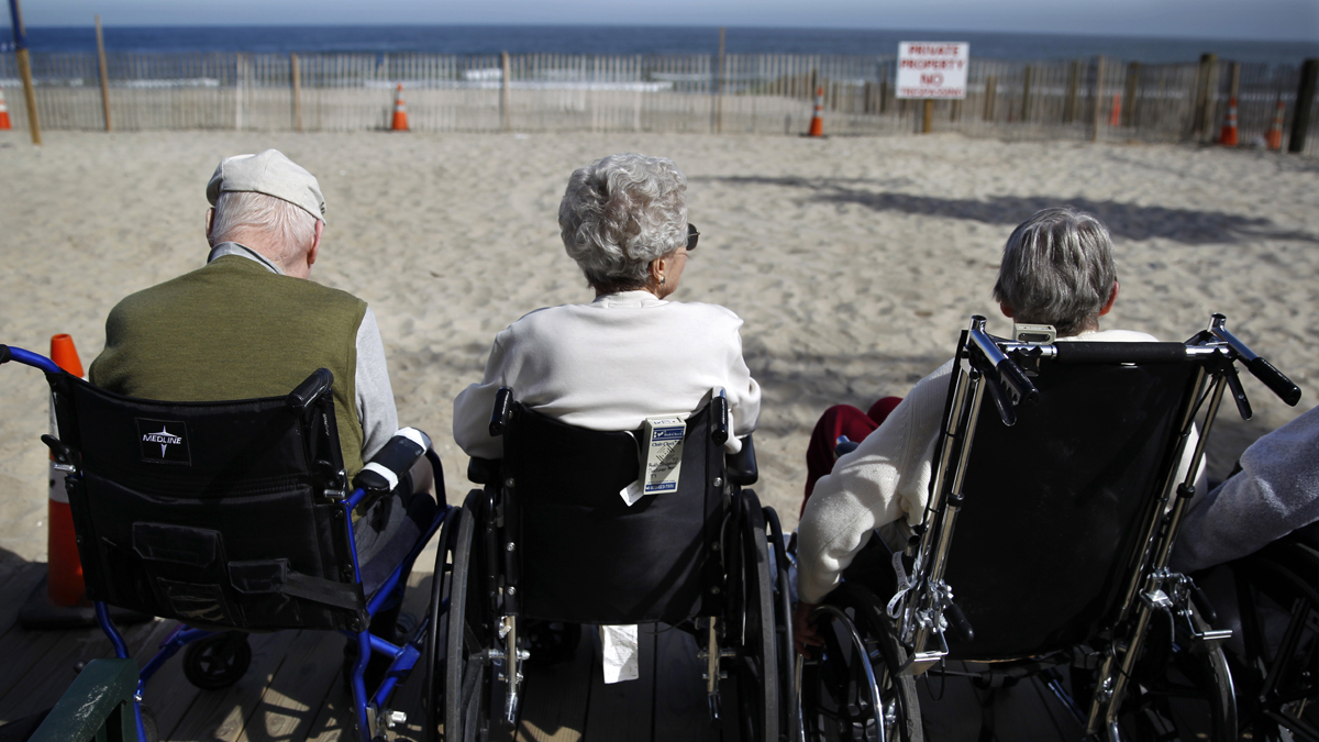 Elderly people from a nearby senior citizen facility sit on the edge of the boardwalk and look out over the ocean on the first day of autumn Tuesday
