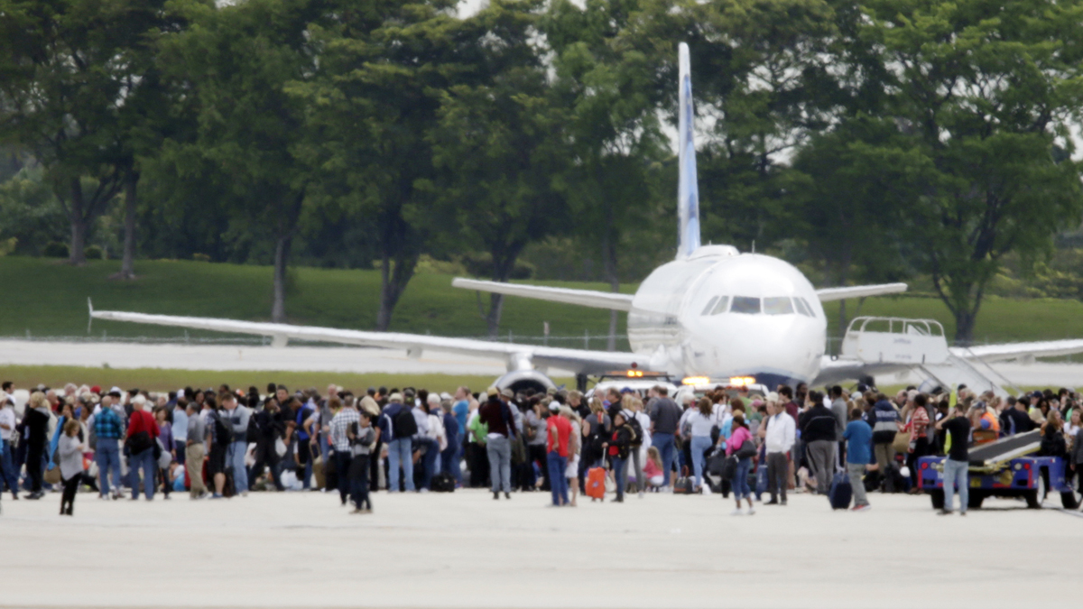 People stand on the tarmac at the Fort Lauderdale-Hollywood  International Airport  after a lone shooter opened fire inside the terminal