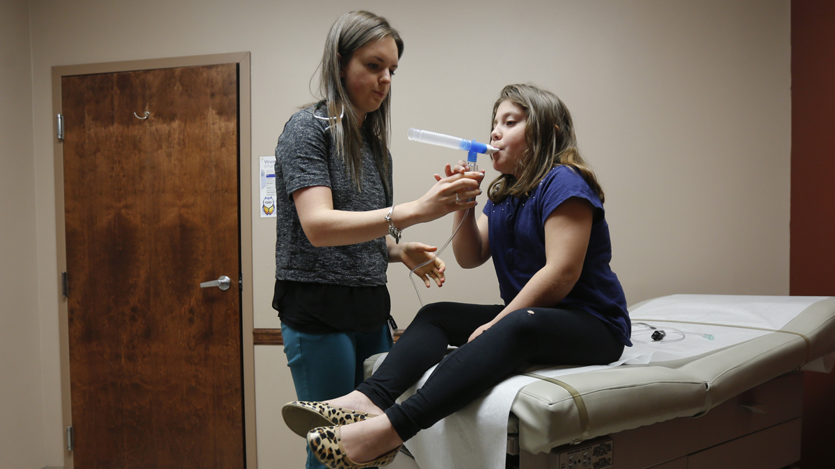  A physician assistant administers a nebulizer treatment to a patient. (Mike Groll/AP Photo) 