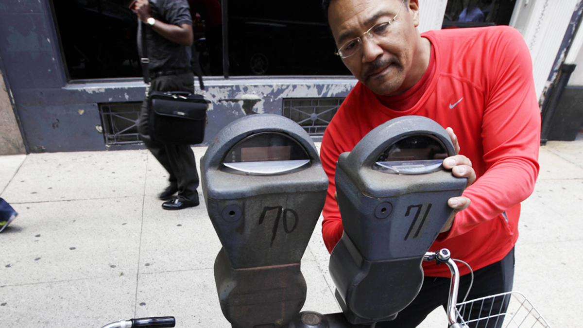  A motorist feeds a parking meter in Philadelphia in this 2009 photo. The city has since installed multi-space kiosks where drivers can pay electronically, but these old vestiges still linger in some neighborhoods. The Parking Authority is now looking into a new round of high-tech parking meters. (Matt Rourke/AP Photo)  