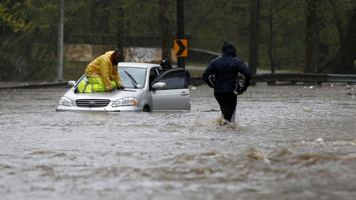 A man walks across a flooded section of the Cobbs Creek Parkway as a tow truck worker tries to free a swamped car, Wednesday, April 30, 2014, in Philadelphia. (AP Photo) 