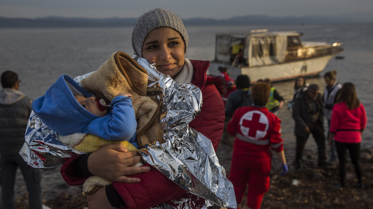 A Syrian woman holds her baby after their arrival on a small boat from the Turkish coast on the northeastern Greek island of Lesbos Monday