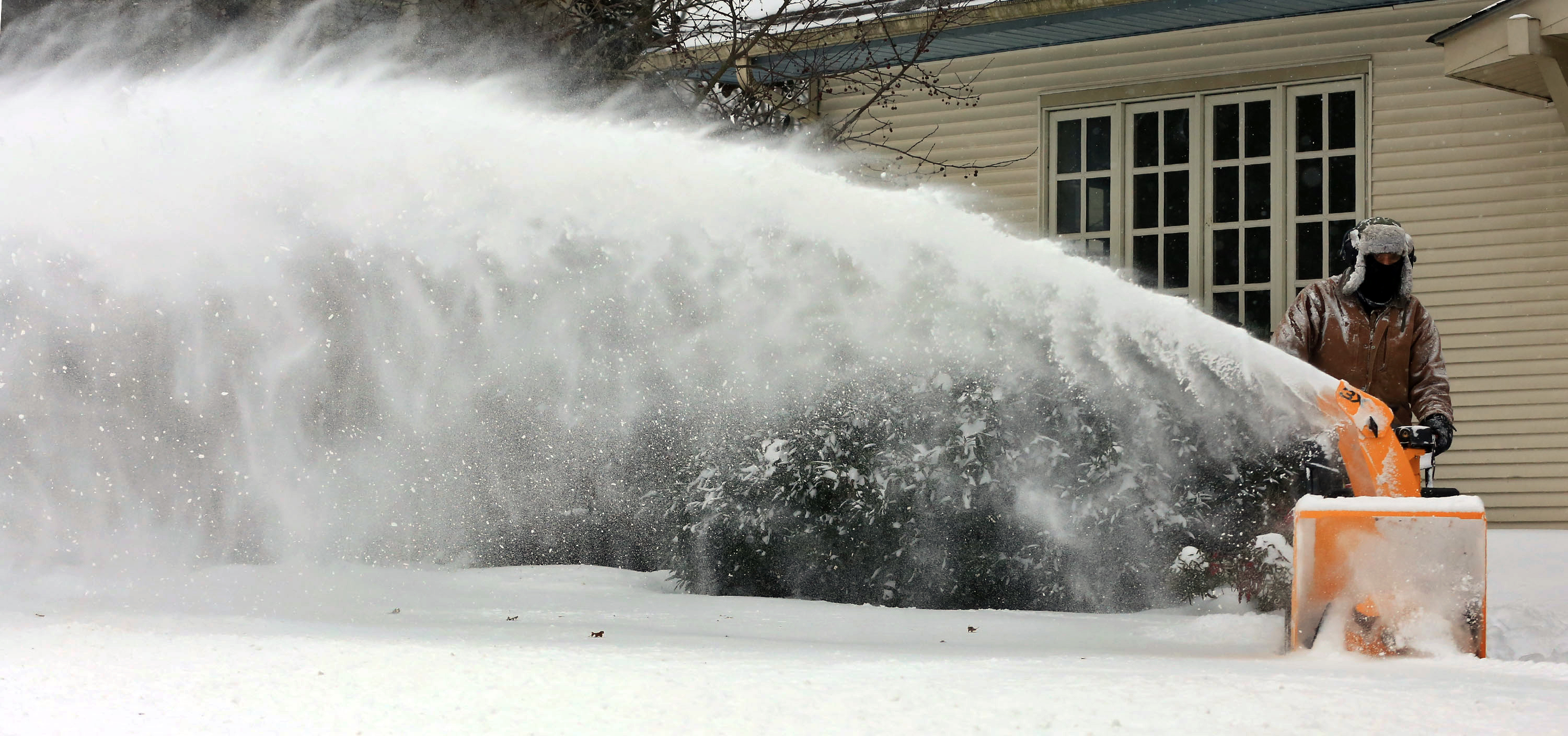 Gary Buss uses a snow blower to clear walkways and sidewalks in front of his properties on Main Street during a winter storm, Friday Jan. 22, 2016, in Blacksburg, Va. A blizzard menacing the Eastern United States started dumping snow in Virginia, Tennessee and other parts of the South on Friday as millions of people in the storm's path prepared for icy roads, possible power outages and other treacherous conditions. (Matt Gentry/The Roanoke Times via AP)