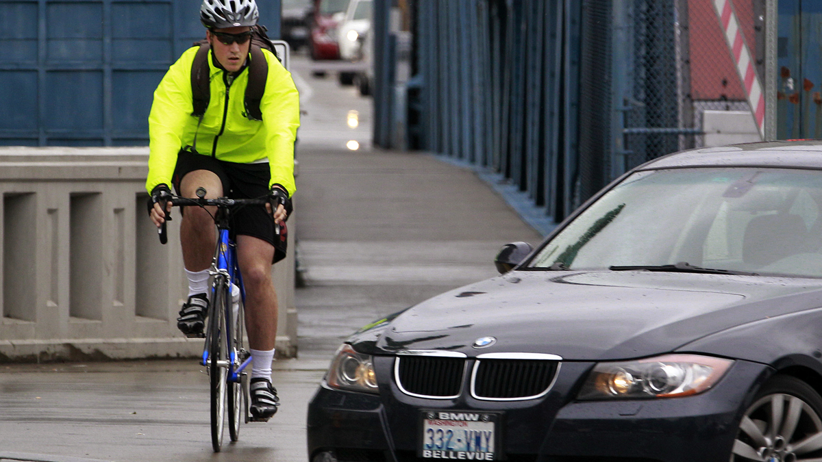  A bicyclist commuting during rush hour keeps an eye on a car turning in front of him in Seattle, Washington. (AP File Photo/Elaine Thompson) 
