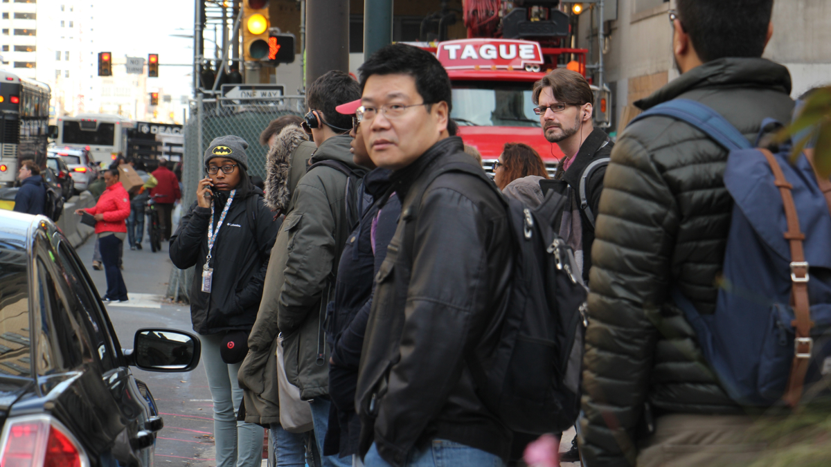 Temple University employees and students wait at Broad and Arch streets for a bus provided by the university. (Emma Lee/WHYY)