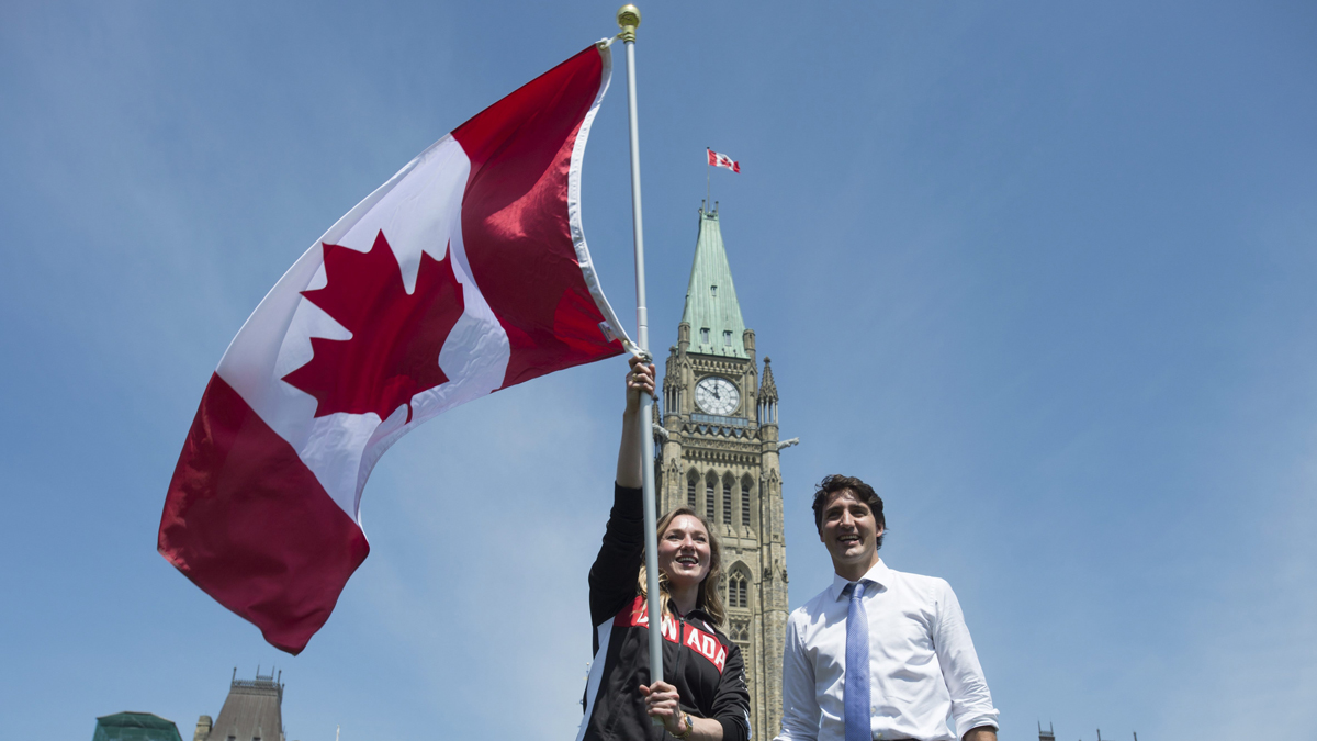 Canadian Prime Minister Justin Trudeau looks on as athlete Rosie MacLennan waves the Maple Leaf in Ottawa after being named as the flag bearer for the 2016 Summer Olympics. (Adrian Wyld/The Canadian Press via AP