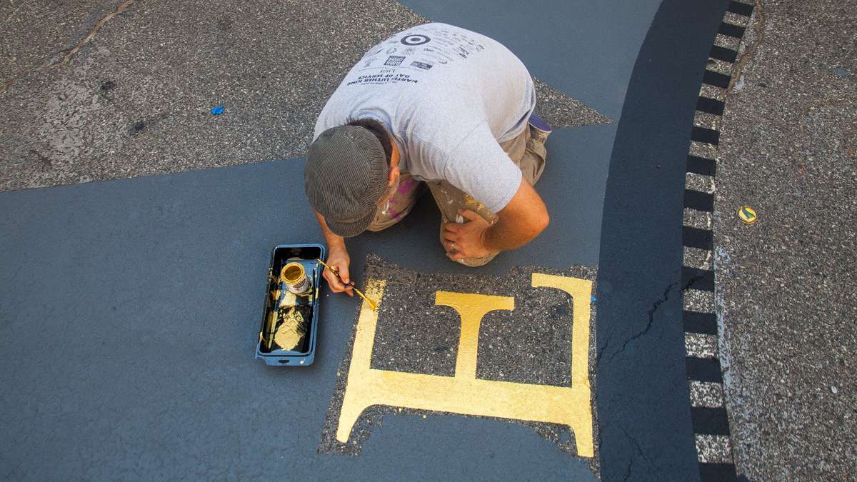  Mural Arts staff artist Nathaniel Lee works on freshening up the eastern marking of the City Hall Compass. (Brad Larrison/for NewsWorks) 