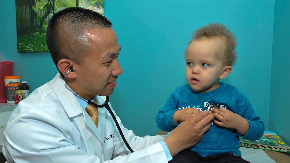 Dr. Clarence Lam takes care of a young patient. (Mathew Karmel/for WHYY)