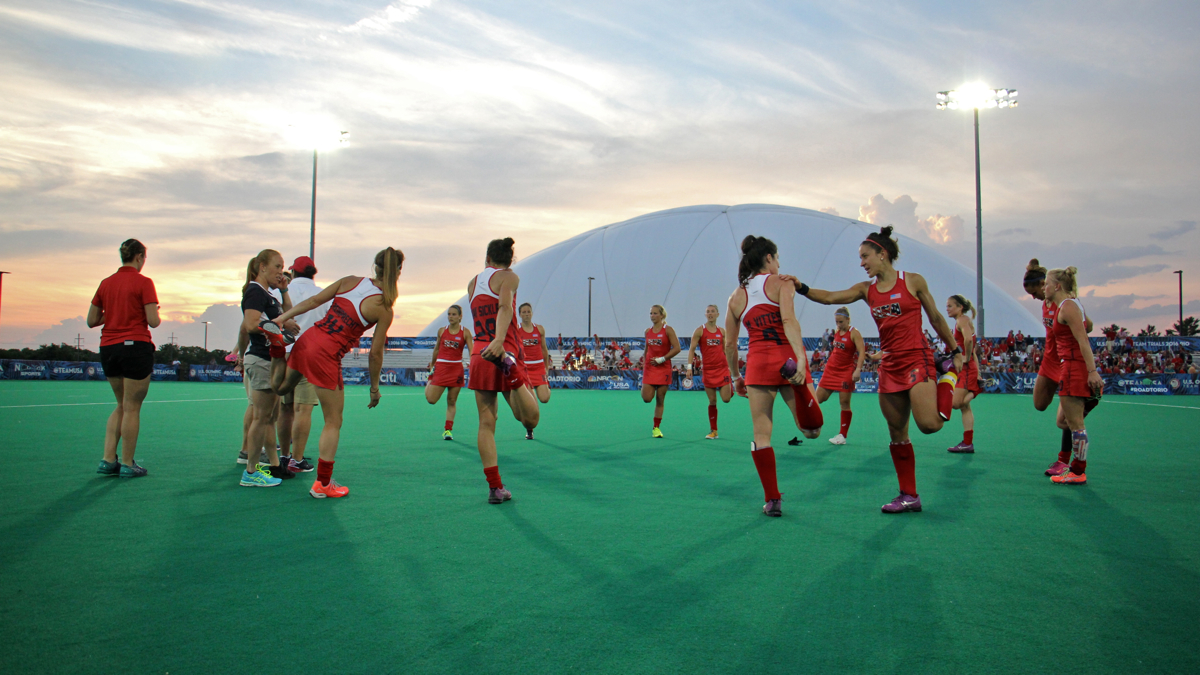 Olympic field hockey players stretch on the turf field at Spooky Nook in Manheim, Pennsylvania. A domed field and indoor training center allow practice year-round. (Emma Lee/WHYY)