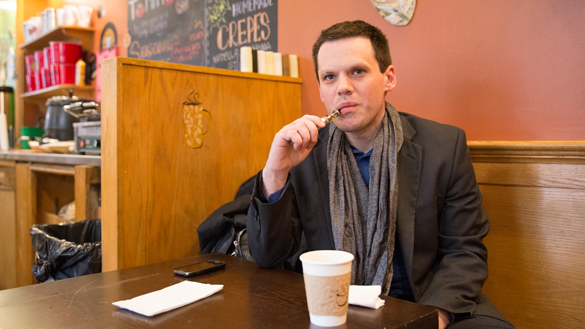  Gregory Conley takes a drag of an electronic cigarette in an Old City cafe.  Philadelphia lawmakers have since banned smoking e-cigarettes indoors and in public spaces similar to tobacco products.  (Lindsay Lazarski/WHYY) 