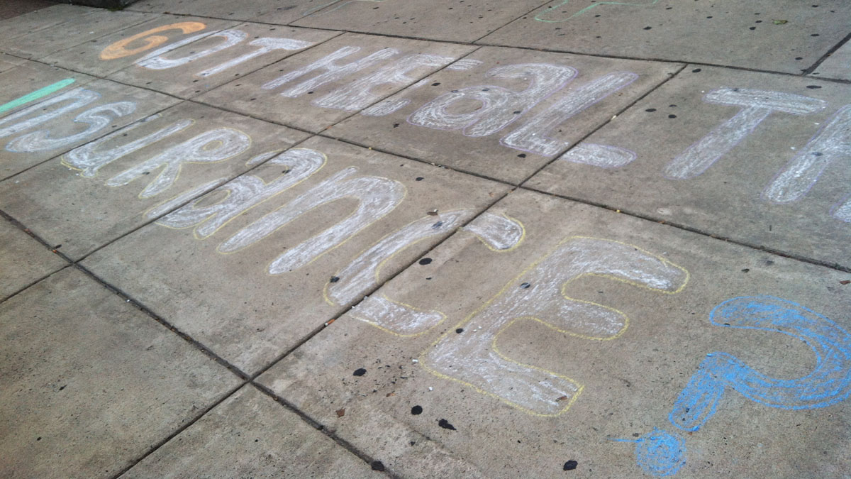 Sidewalk art outside a community center in South Philadelphia in September aims to draw residents in to a town hall about the new health care marketplaces. (Elana Gordon/for The Pulse)