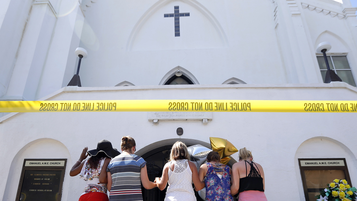 A group of women are shown praying together on the sidewalk in front of the Emanuel AME Church in Charleston