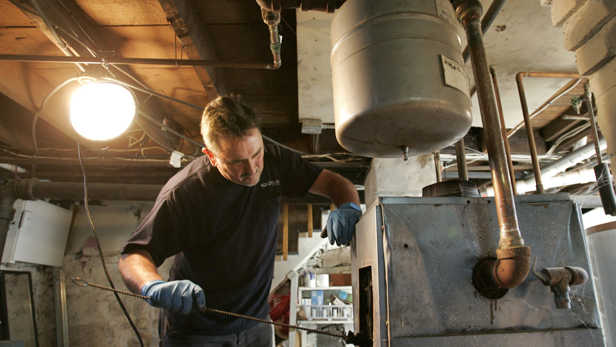 An oil burner technician uses a brush to scrub the inside of an oil burning furnace. This annual tune-up helps maintain the units efficiency. (Steven Senne/AP Photo, file) 