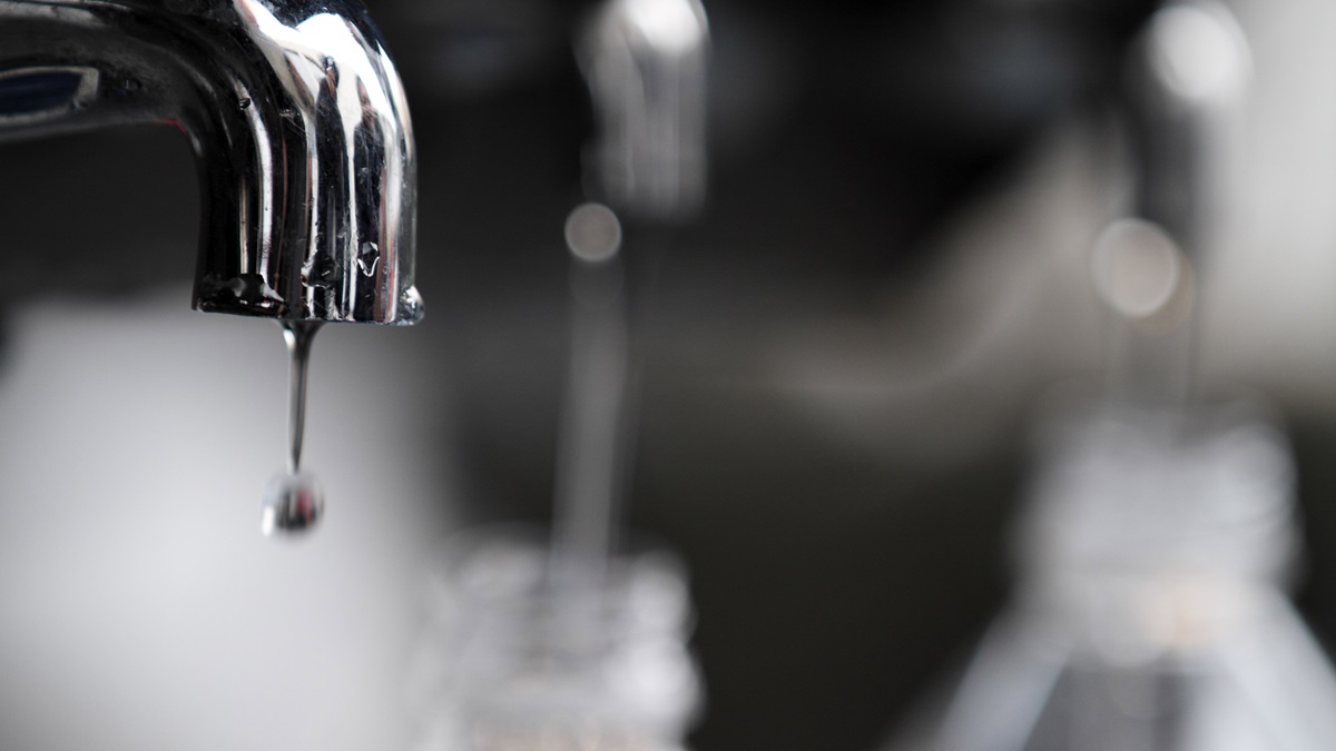 An up-close view of water dripping from a metal faucet
