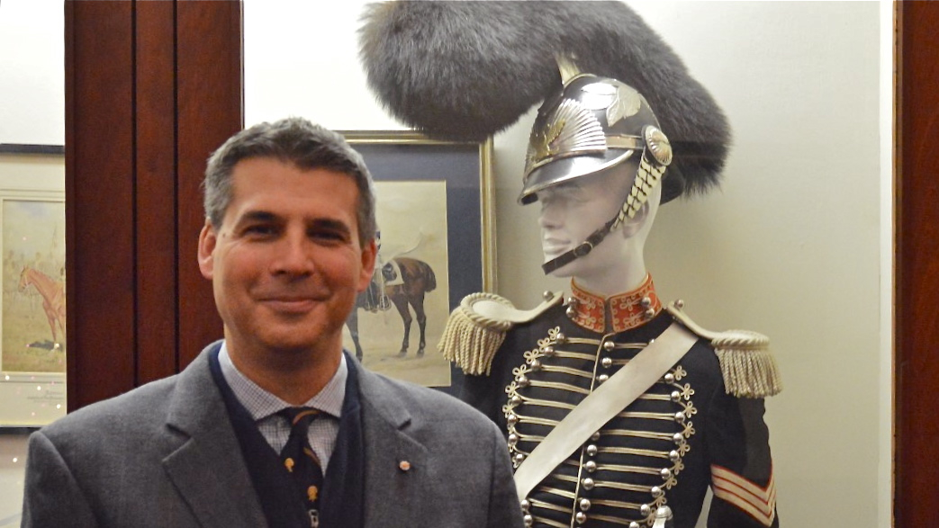 Andre Stephano of the First Troop stands next to the ceremonial uniform designed in 1825 that members of his group will wear in Donald Trump's  inaugural parade Jan. 20. (Tom MacDonald/WHYY)