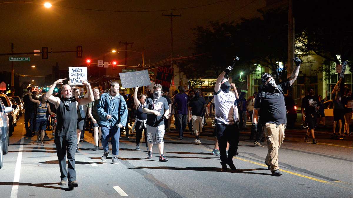 Protesters, including at least four unidentified foreigners (seen on the right) gesture into the light from the PPD helicopter.