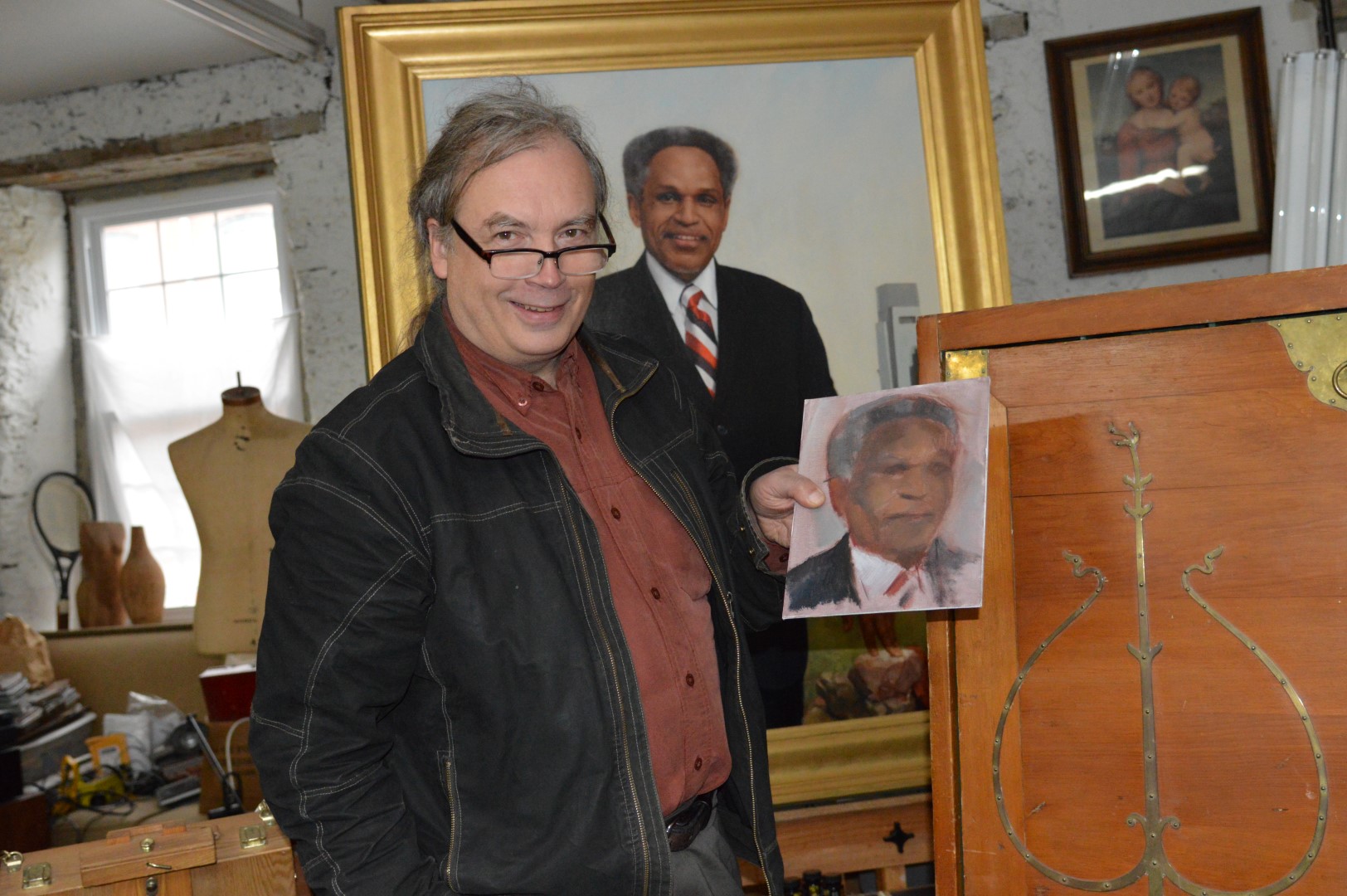 Garth Herrick poses with Street portraits in his Germantown studio. (Tom MacDonald/WHYY)