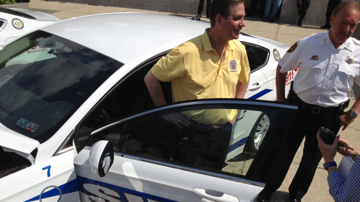 Montgomery County Commissioner Bruce Castor Jr., left, and Sheriff Russell Bono show off one of the county sheriff's department's three new gas-electric hybrids. (Bill Hangley/WHYY) 