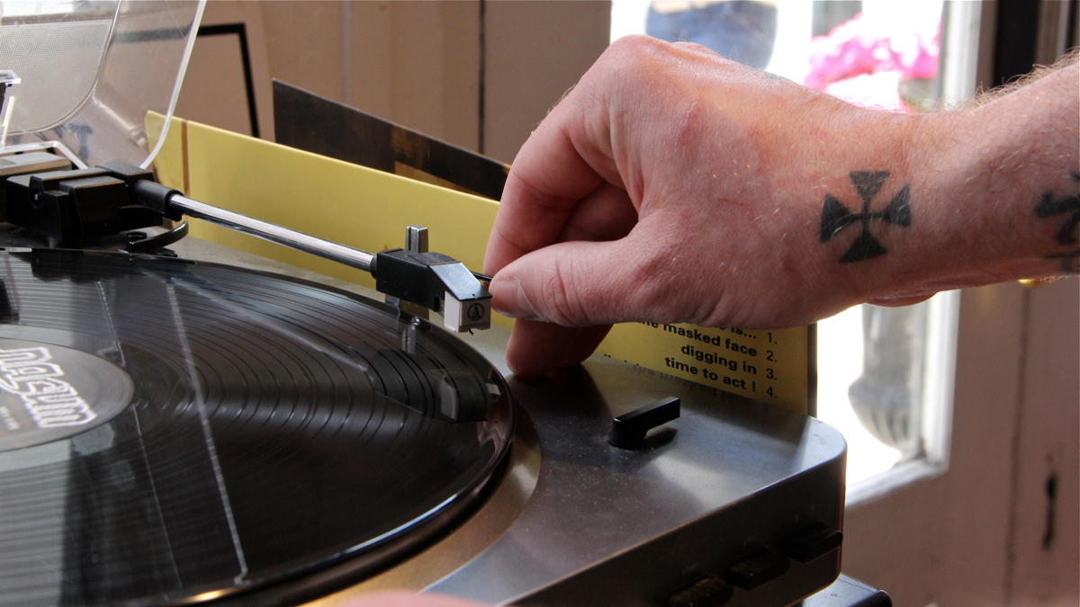  Isaac Williams puts a record on at AKA Music in Old City. (Emma Lee/WHYY) 