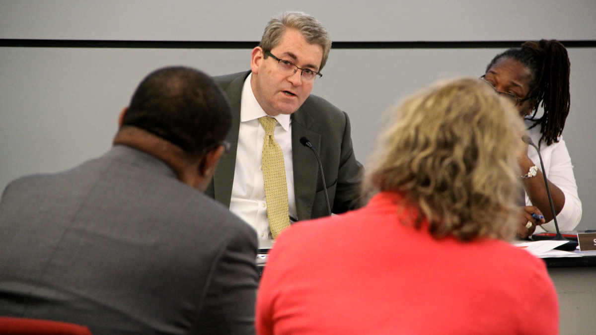 SRC member Bill Green grills Delaware Valley Charter High School CEO Ernest Holiday during a hearing in which the school's charter was revoked. (Emma Lee/WHYY)