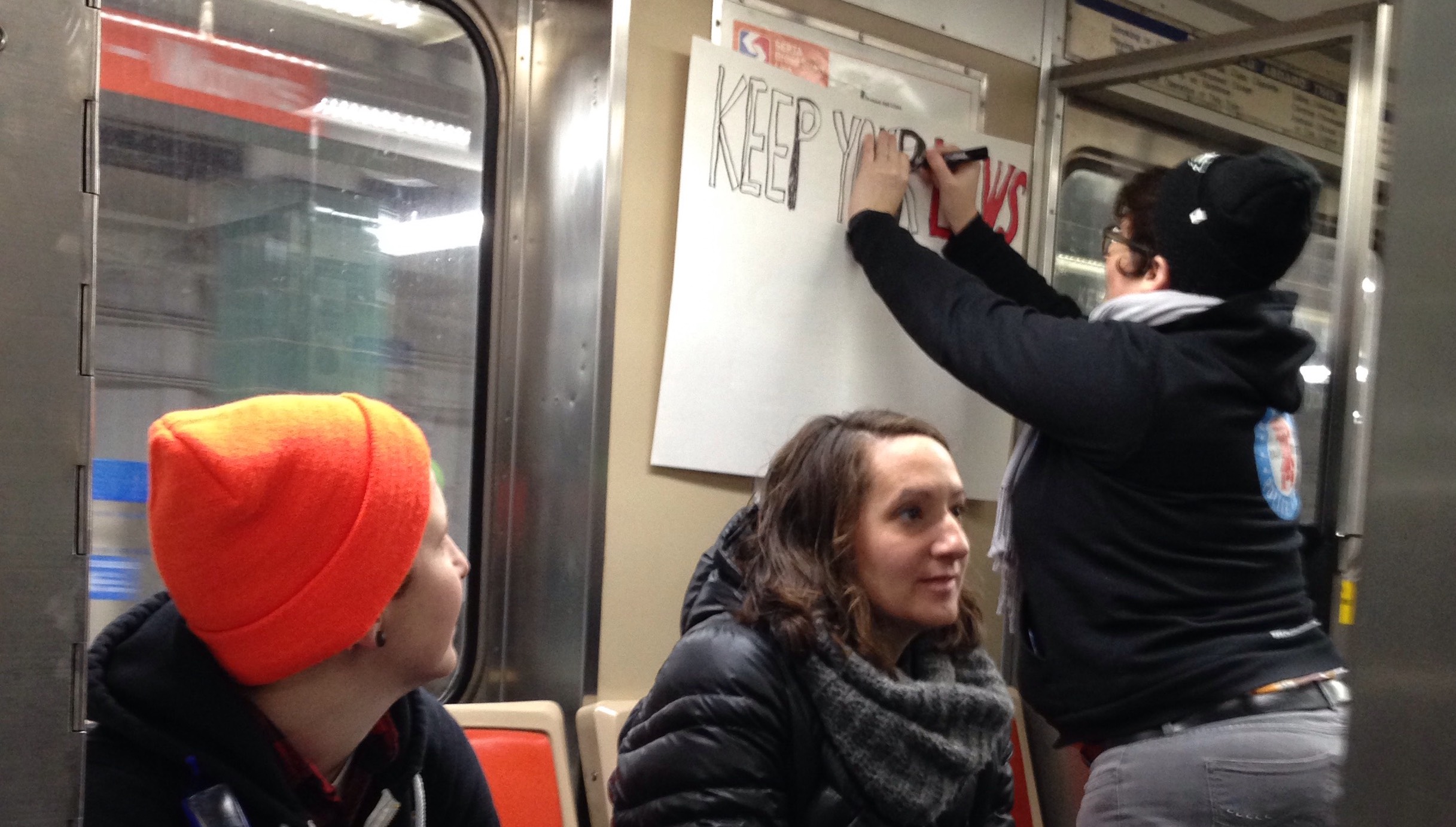 A woman creates a sign on the Broad Street Line for the Women's March on Philadelphia on the way to City Hall. (Alaina Mabaso for NewsWorks)