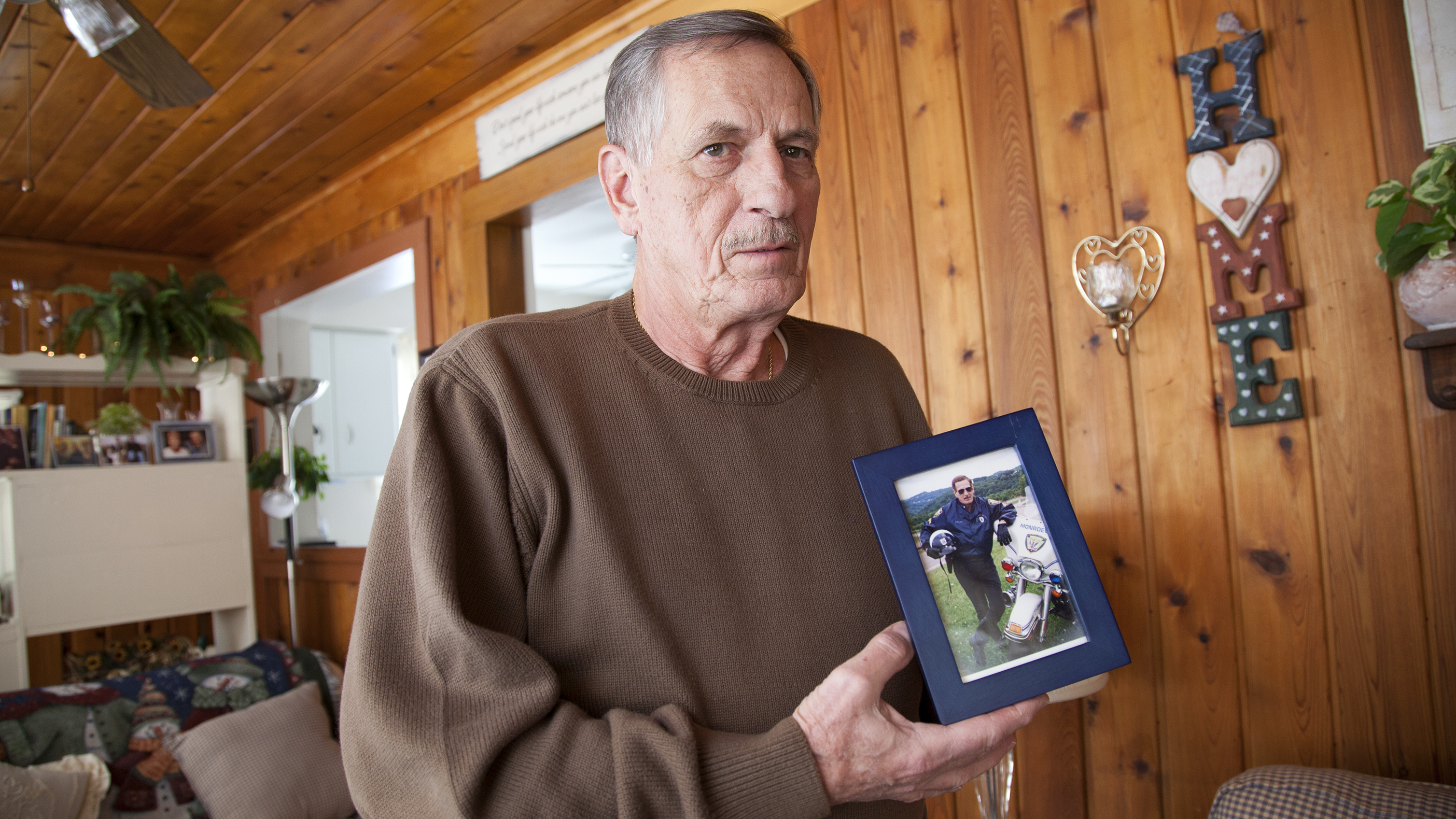  Joe Rosipal, 70, a retired Monroeville police officer, with a photograph of himself in his 40s, when he was part of the motorcycle division. (Irina Zhorov/WESA) 