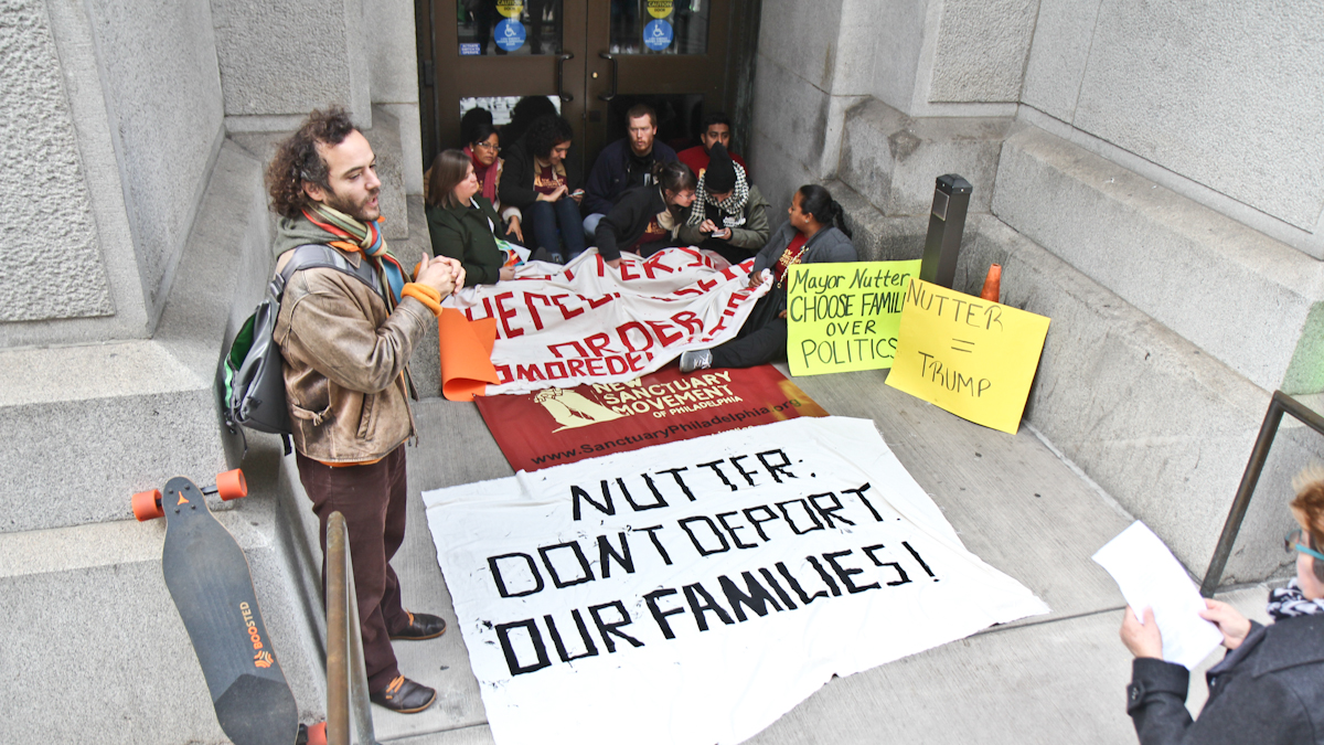Immigration activists with the New Sanctuary Movement block the visitor entrance to City Hall Friday. (Kimberly Paynter/WHYY)