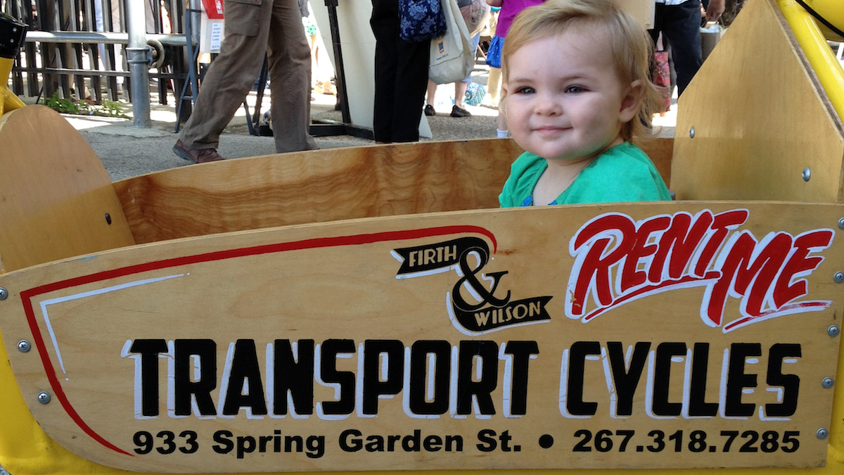 Juniper Driscoll in a cargo bike at Firth & Wilson. (Dena Driscoll/for NewsWorks)
