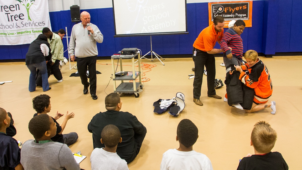 Students, faculty and Flyers personel compete in a competition to see who can dress a student in hockey gear the fastest. (Brad Larrison/for NewsWorks)