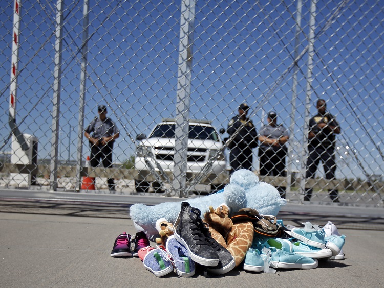 Shoes and a teddy bear, brought by a group of U.S. mayors, are piled up outside a holding facility for immigrant children in Tornillo, Texas, near the Mexican border, Thursday, June 21, 2018.  Mayors from more than a dozen U.S. cities including New York and Los Angeles gathered near the holding facility to call for the immediate reunification of immigrant children with their families (Andres Leighton/AP Photo)