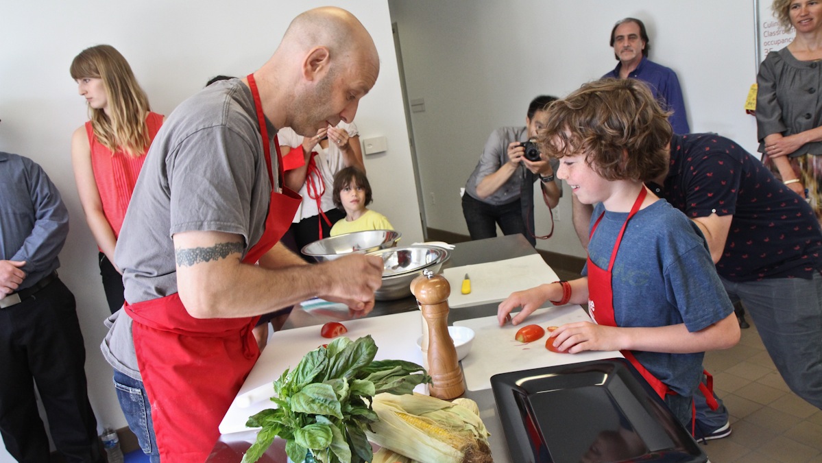 Philly restaurateur Marc Vetri demonstrates how to chop tomatoes watched by Grant Kane, 9, at the Philadelphia Library's new Culinary Literacy Center. (Kimberly Paynter/WHYY) 